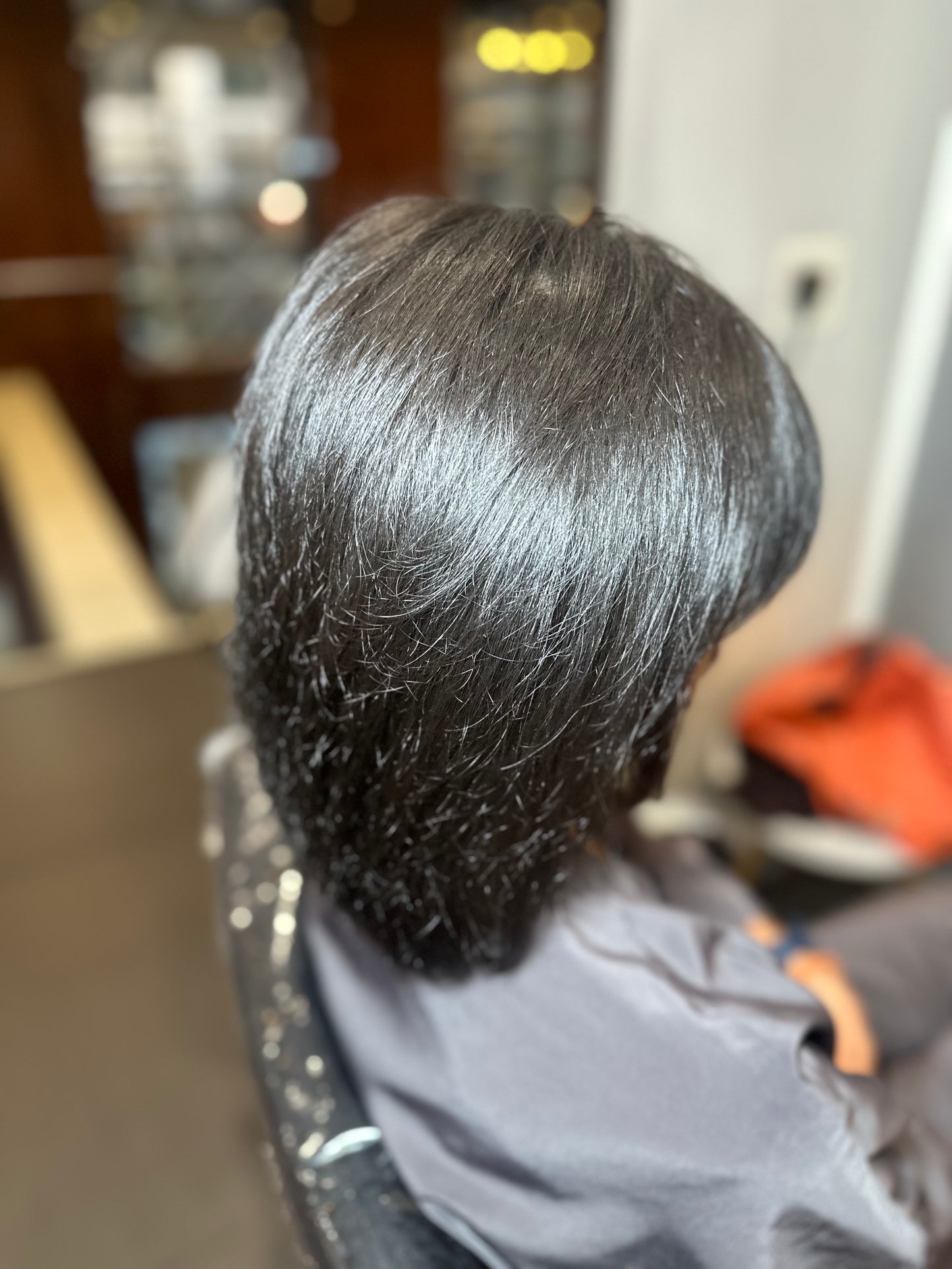 Person with freshly styled hair in a salon setting after using hair growth spray