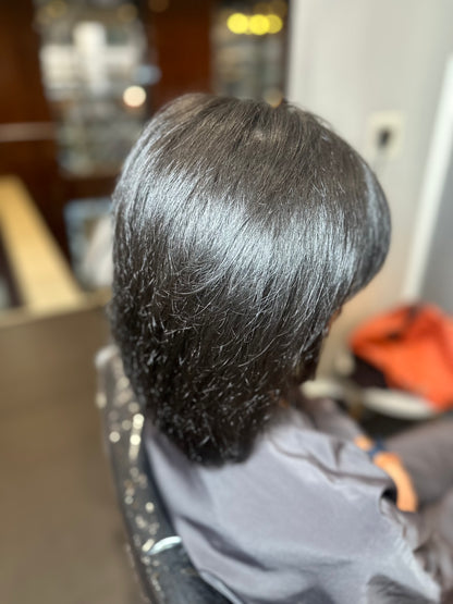 Person with freshly styled hair in a salon setting after using hair growth spray